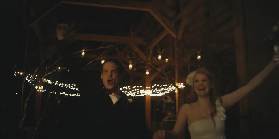 A bride and groom hold hands and cheer