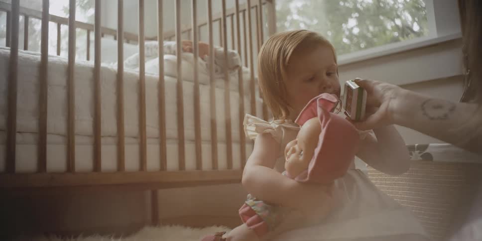 Woman playing with a toddler in a bedroom on a sunny day