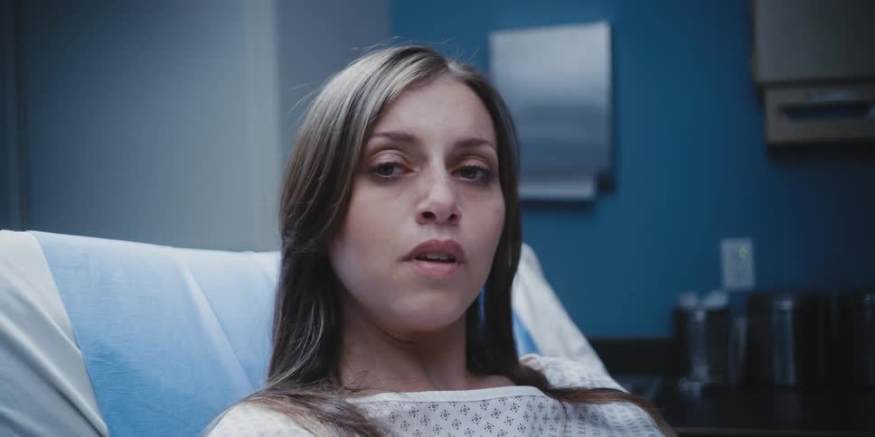 A woman in a hospital room sighs