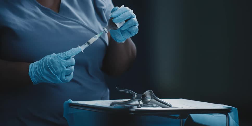 A nurse prepares a syringe and hands it to a doctor