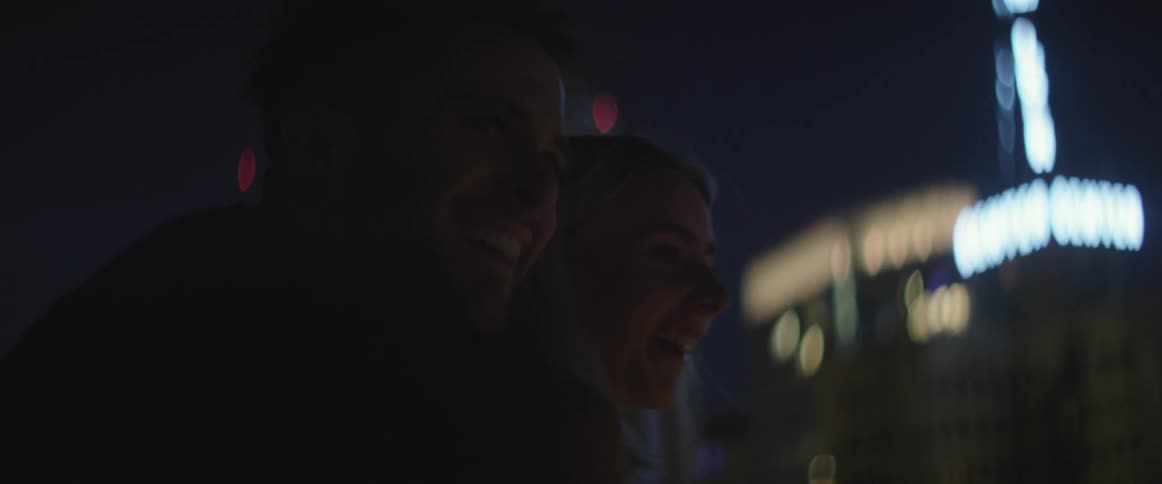 Couple standing outside at night in a large city