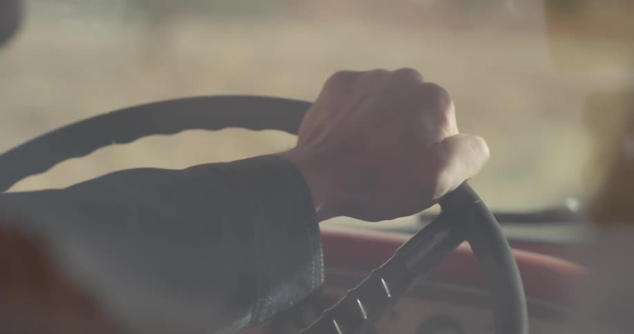 A hand is steering the wheel of a vehicle