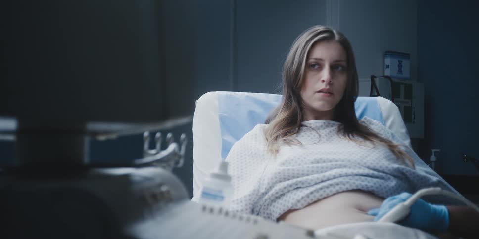 A pregnant woman looks worried while getting an ultrasound