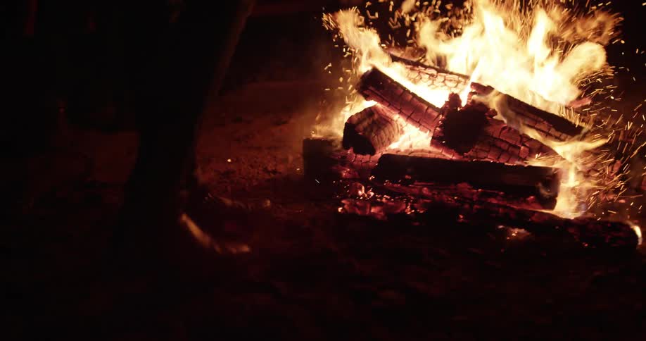 Person kicking the wood in a campfire