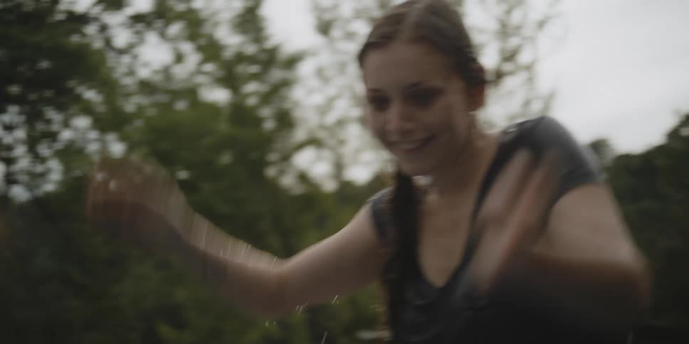 A woman and a girl splash each other while playing outside