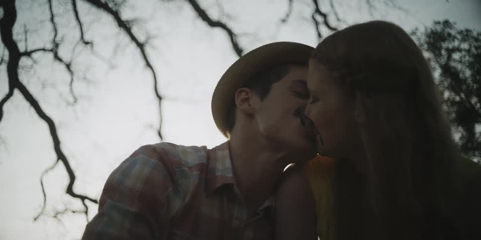 A man kisses a woman under a tree