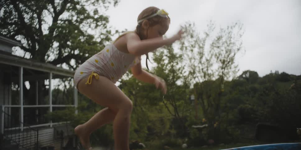 A child climbs a step ladder and jumps in the pool