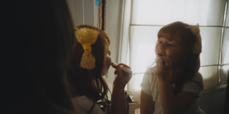 A mom puts on lipstick and lets her daughter put some on