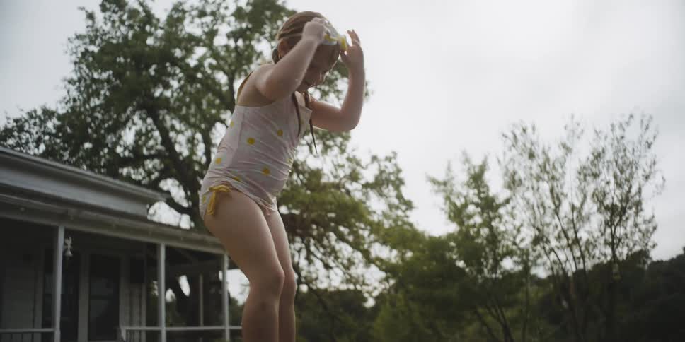 A child playing in  a small pool in the yard