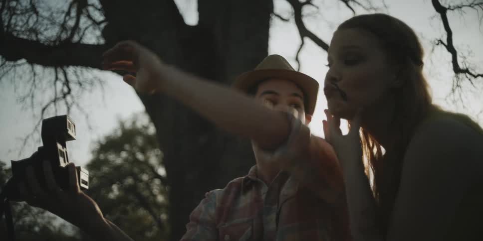Man and woman with face mustaches pose for a camera outside