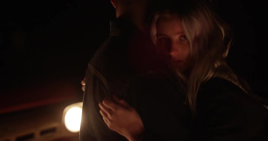 Couple embracing at night as seen  courtesy of the headlights of their vehicle