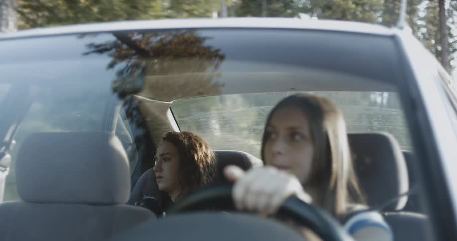 A woman is driving with a girl in the backseat