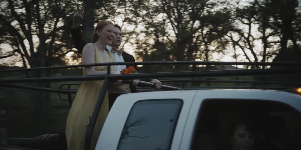 Teenages dressed for prom ride in the back of a pickup truck