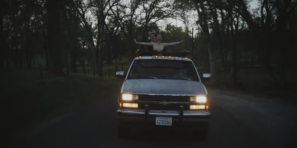 A young couple hang off the back of a pickup truck