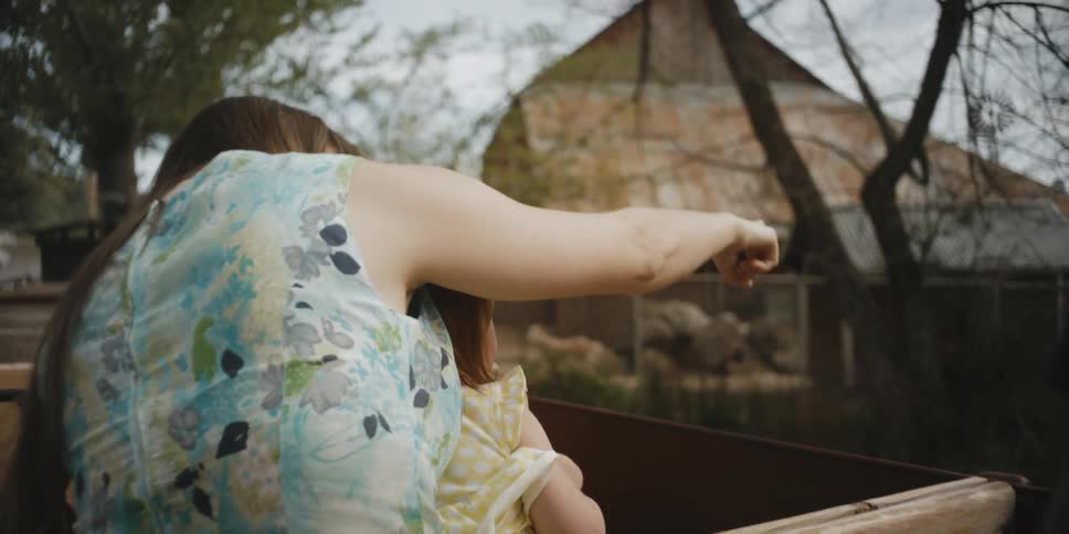 A woman is pointing out things to a child in a pickup truck