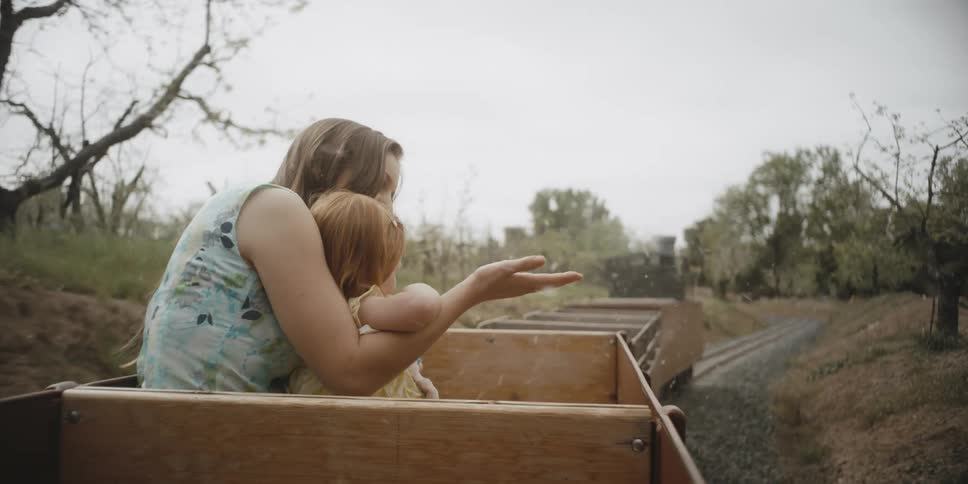 A mother and child ride in an amusement park-type train