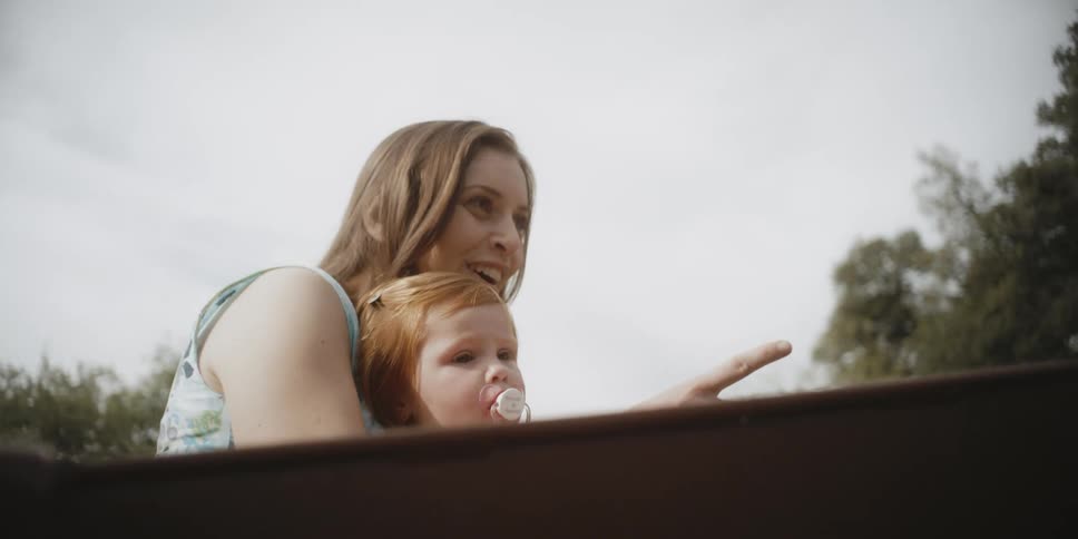 A woman and baby look at the sites as they ride in back of a truck