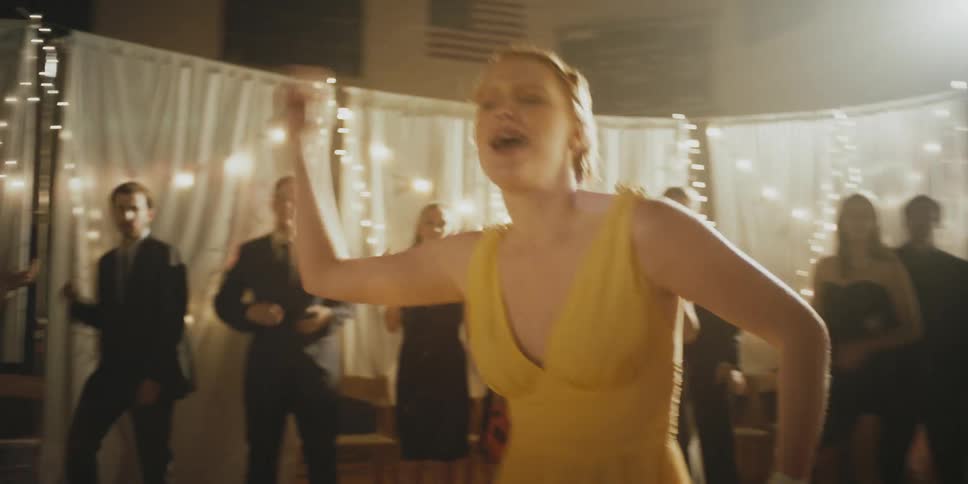 A woman in a yellow dress dances at a party