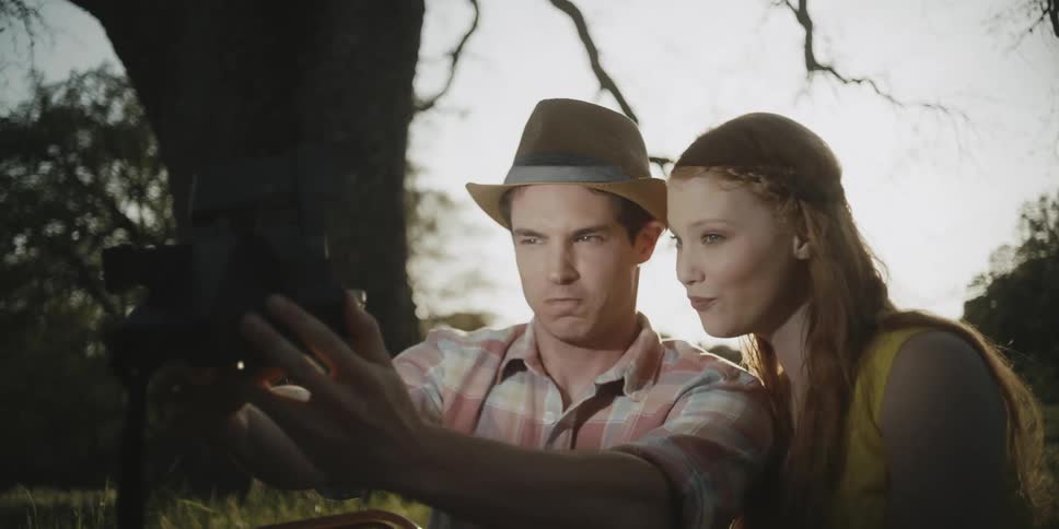 A man and woman take a selfie by a tree