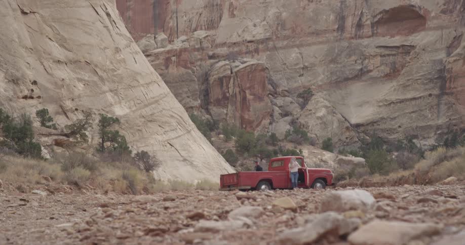 People get out of a red truck by a canyon