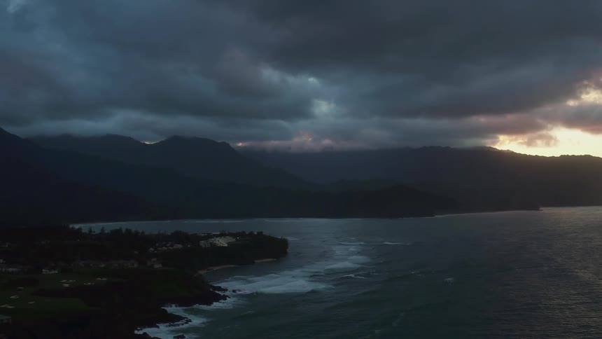 Panning view  of some very dark  clouds above a mountainous beach area