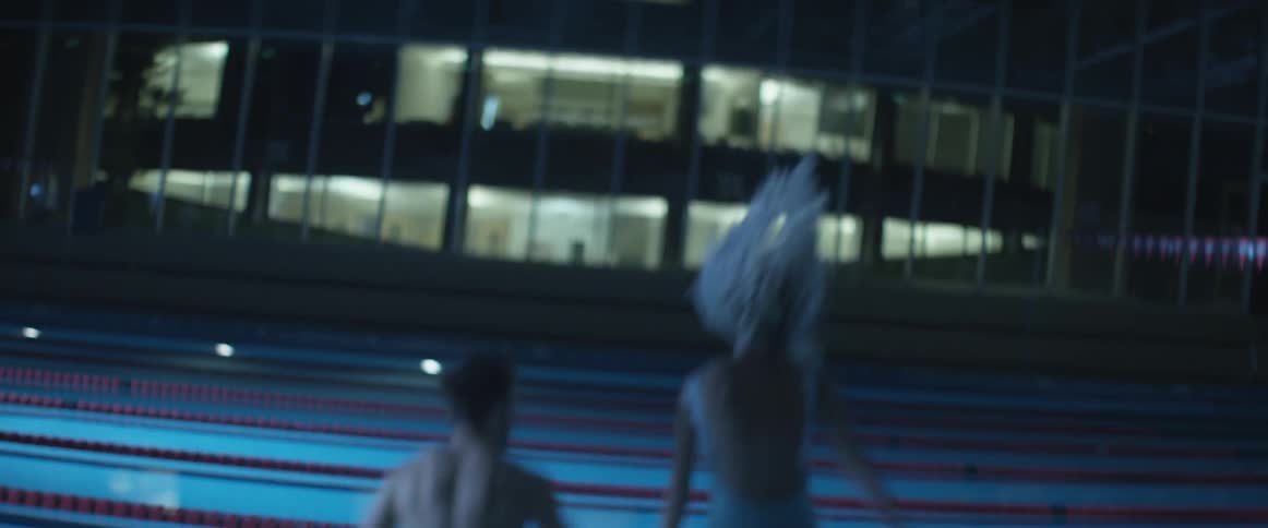 Man and woman holding hands jump into a pool
