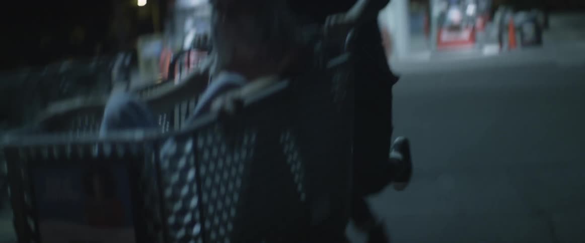 Man pushing woman in shopping cart in parking lot