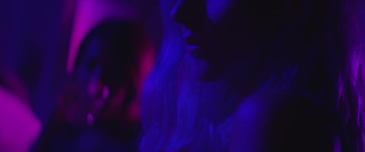 Blonde woman sitting with others in a dark club
