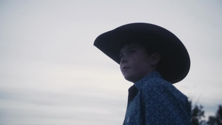 Young cowboy standing in an open area