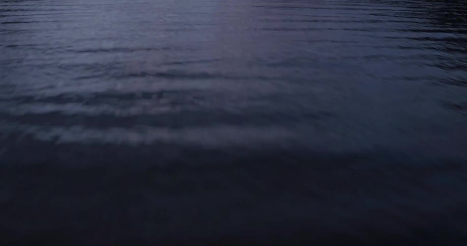 Aerial view moving over a large body of water then looking up to a cloudy sky