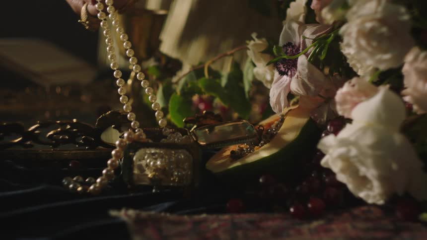 A woman pulls a string of pearls from a display adorned with flowers