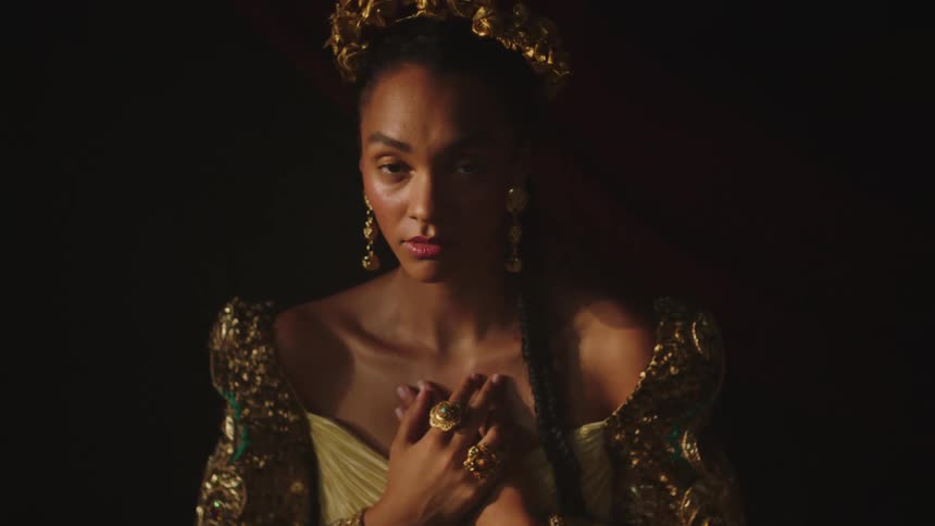 A woman wearing an ornate dress and jewelry poses for the camera