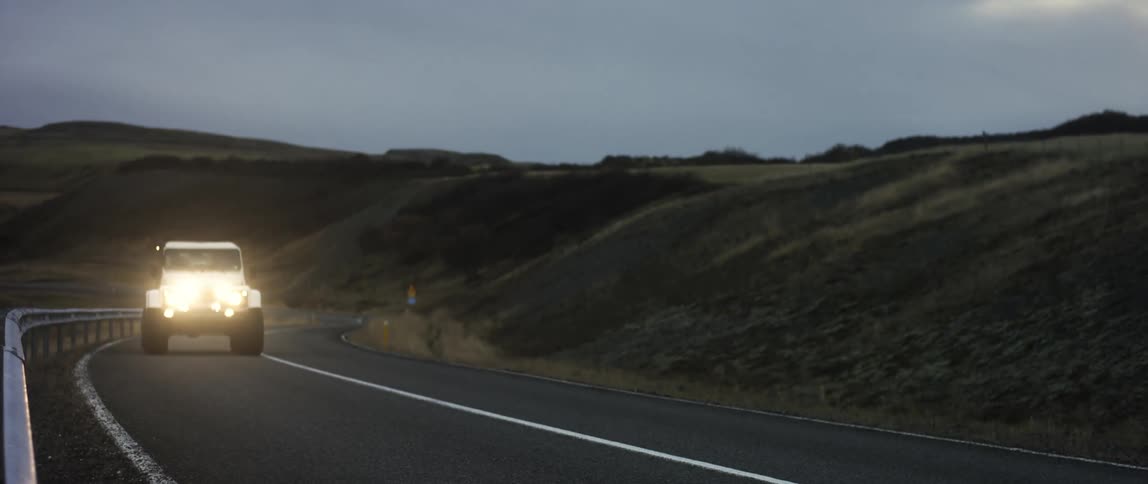 A car is driving on a road in a rural area