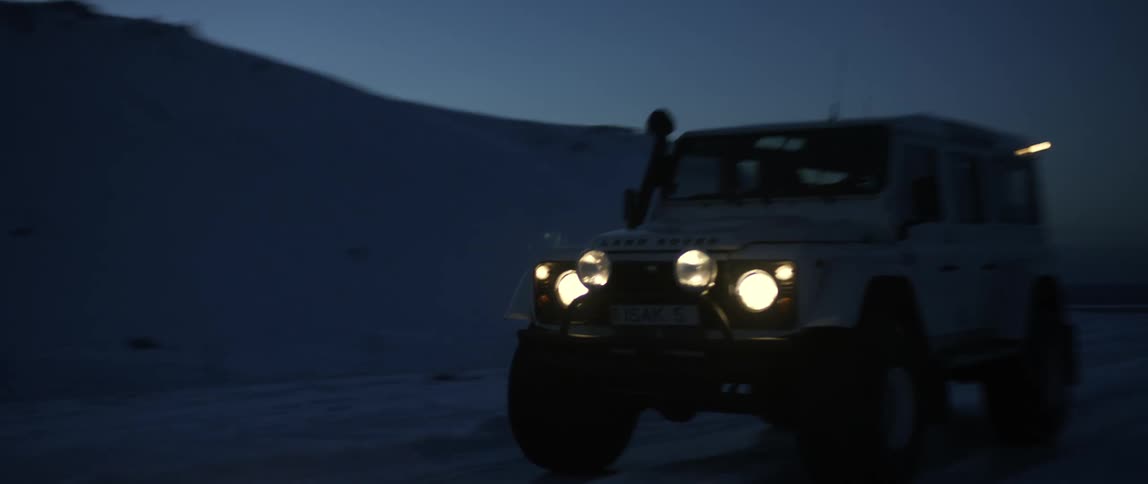 A vehicle drives on the snow filled road