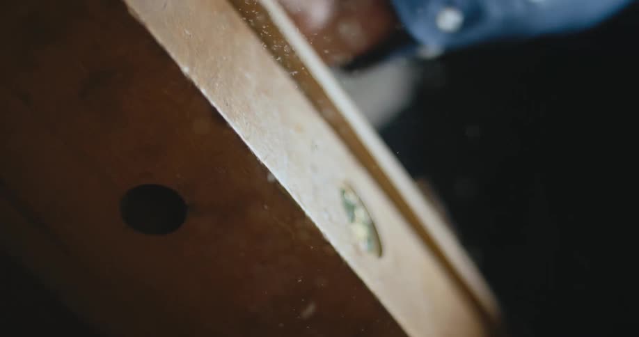 A carpenter brushes wood shavings off of a table