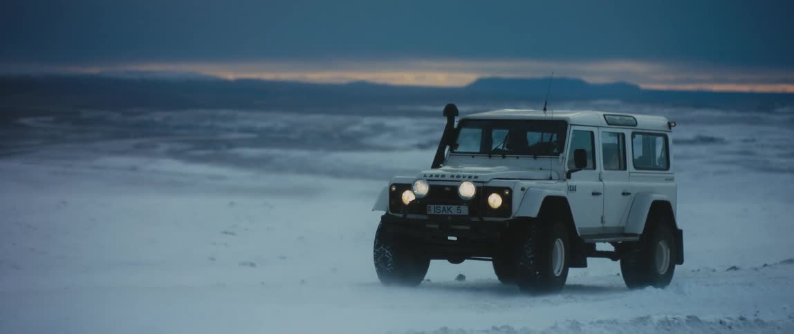 A vehicle is parked in an arctic area at dusk