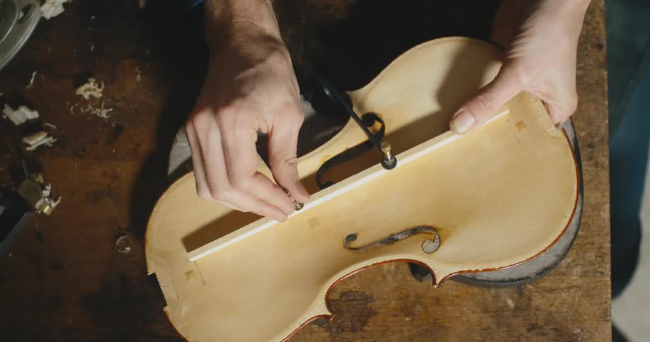 A man applies a piece as he makes a musical instrument
