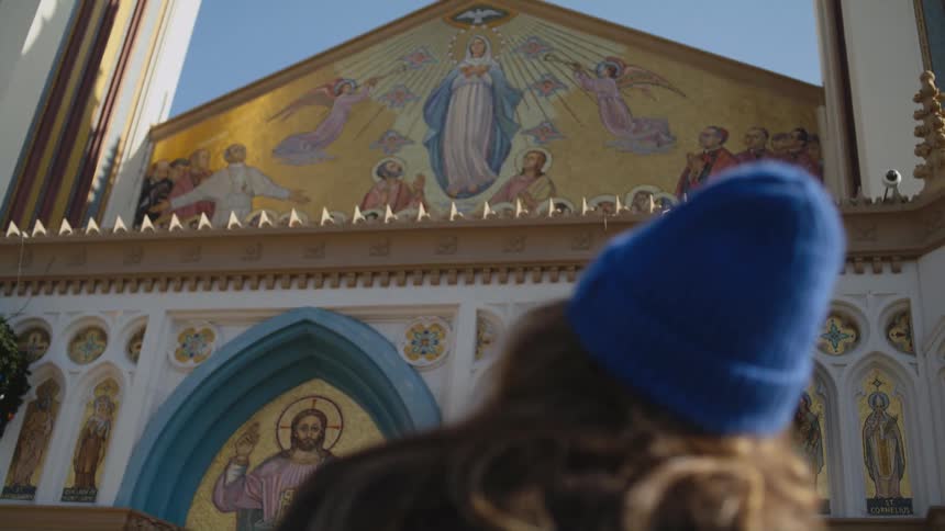 A woman is standing outside of a church in a city