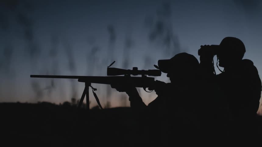 Two men are using a rifle to hunt