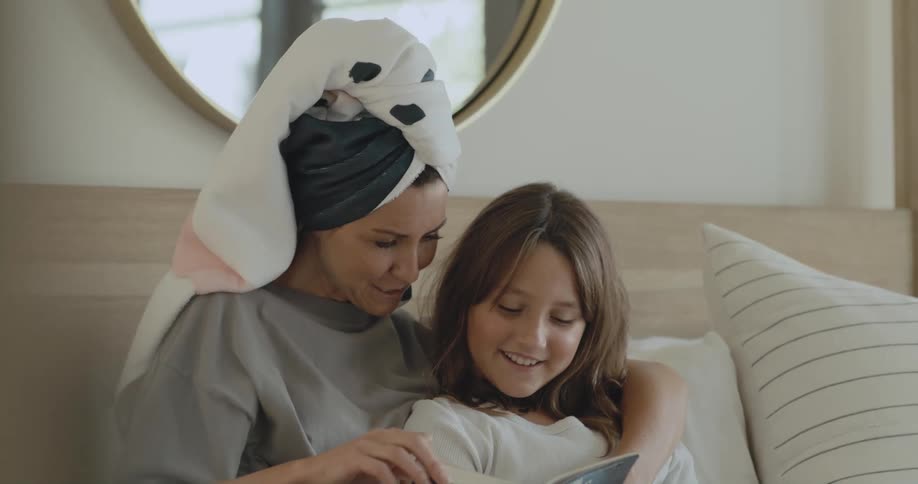 Mother and daughter are sitting and reading a book together