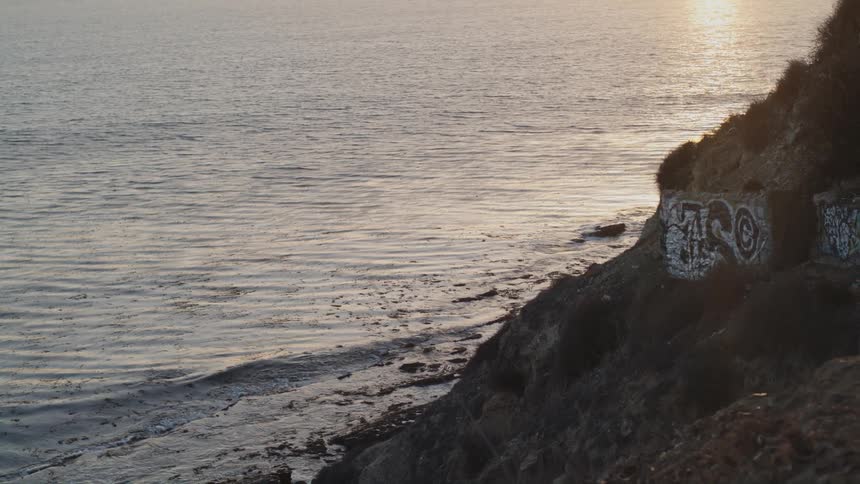 A rocky slope leading down towards the ocean during the day
