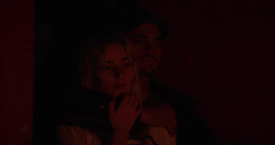 A man and women stand before a campfire at night