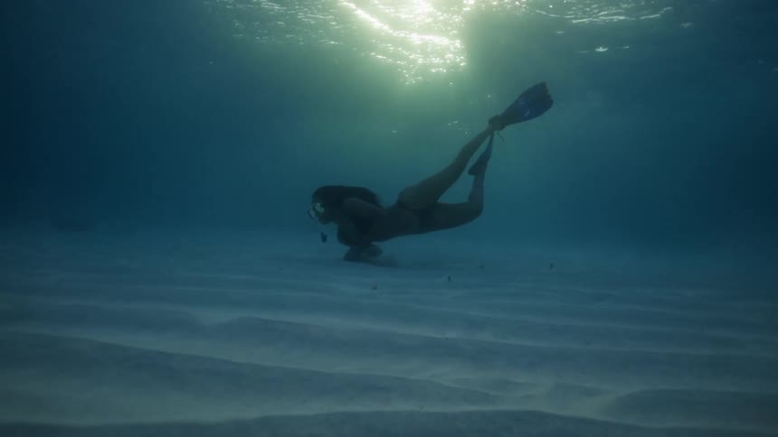 A woman is swimming underwater in the ocean