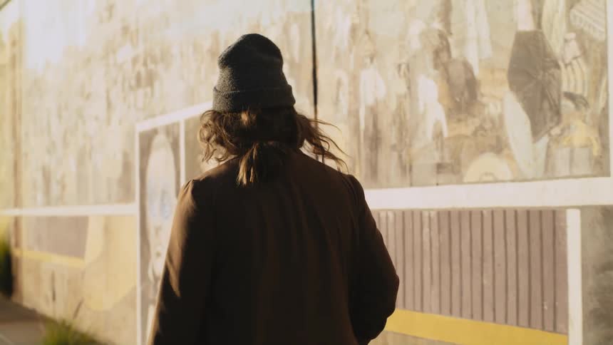 Man walking next to building with presidents painted on wall