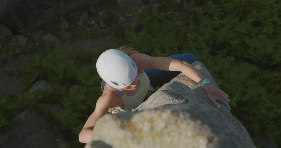 A woman is rock climbing up the cliff