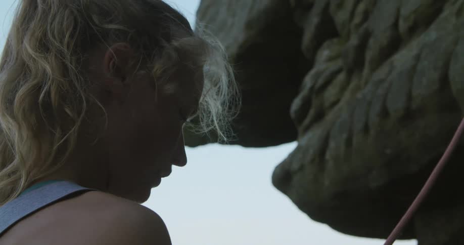 A woman is rock climbing a cliff outdoors