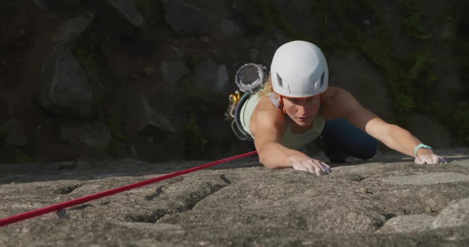 A woman is rock climbing up the cliff
