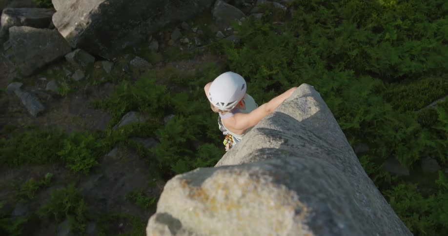 A woman is hanging off the side of the mountain