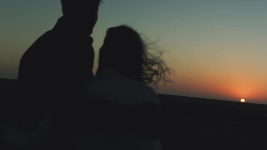 A couple watch the sun set on a windy day
