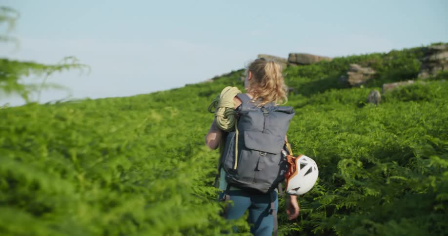 A woman is hiking through the grass